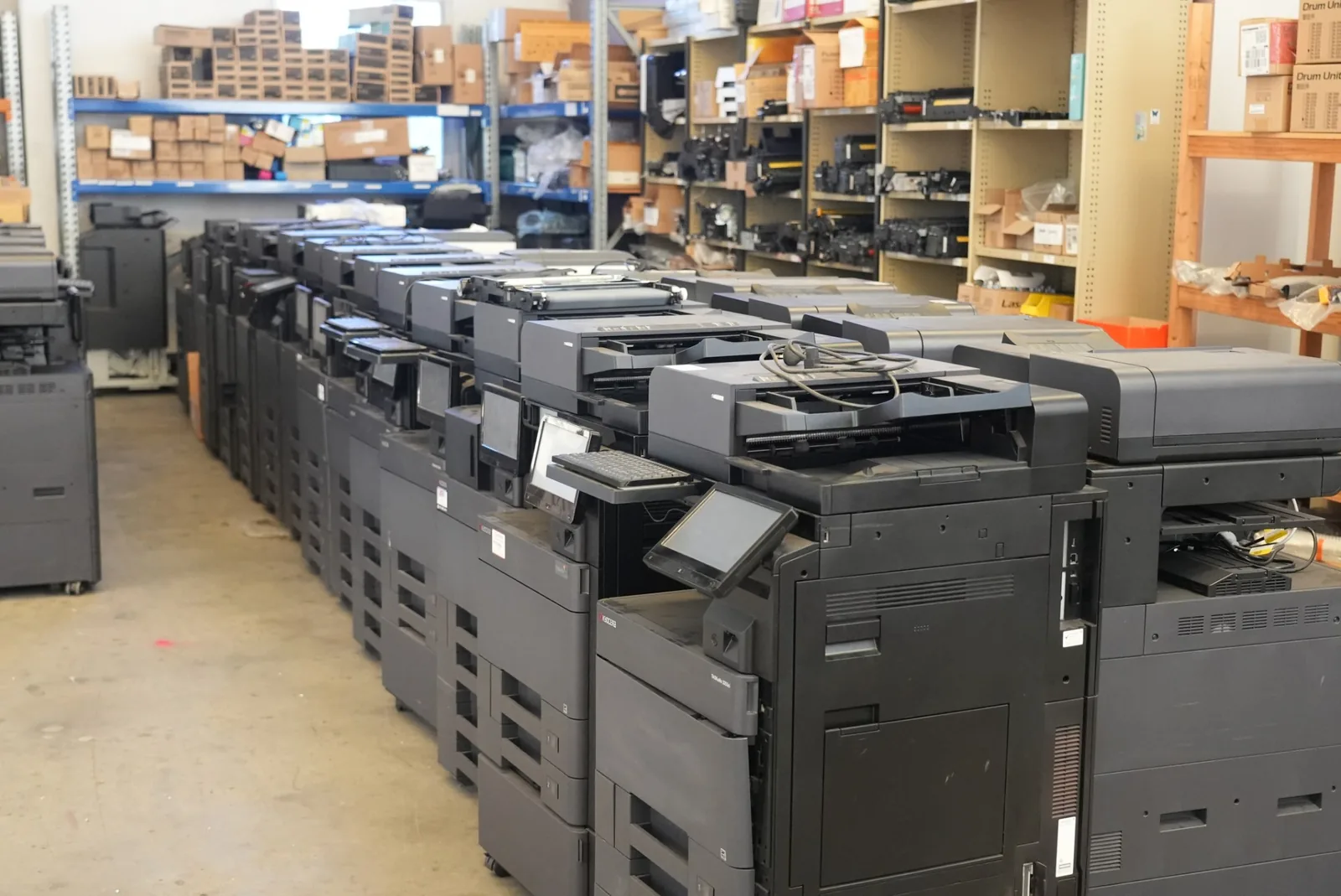 Close view along a row of Kyocera TASKalfa multifunction printers with their touch screen control panels raised